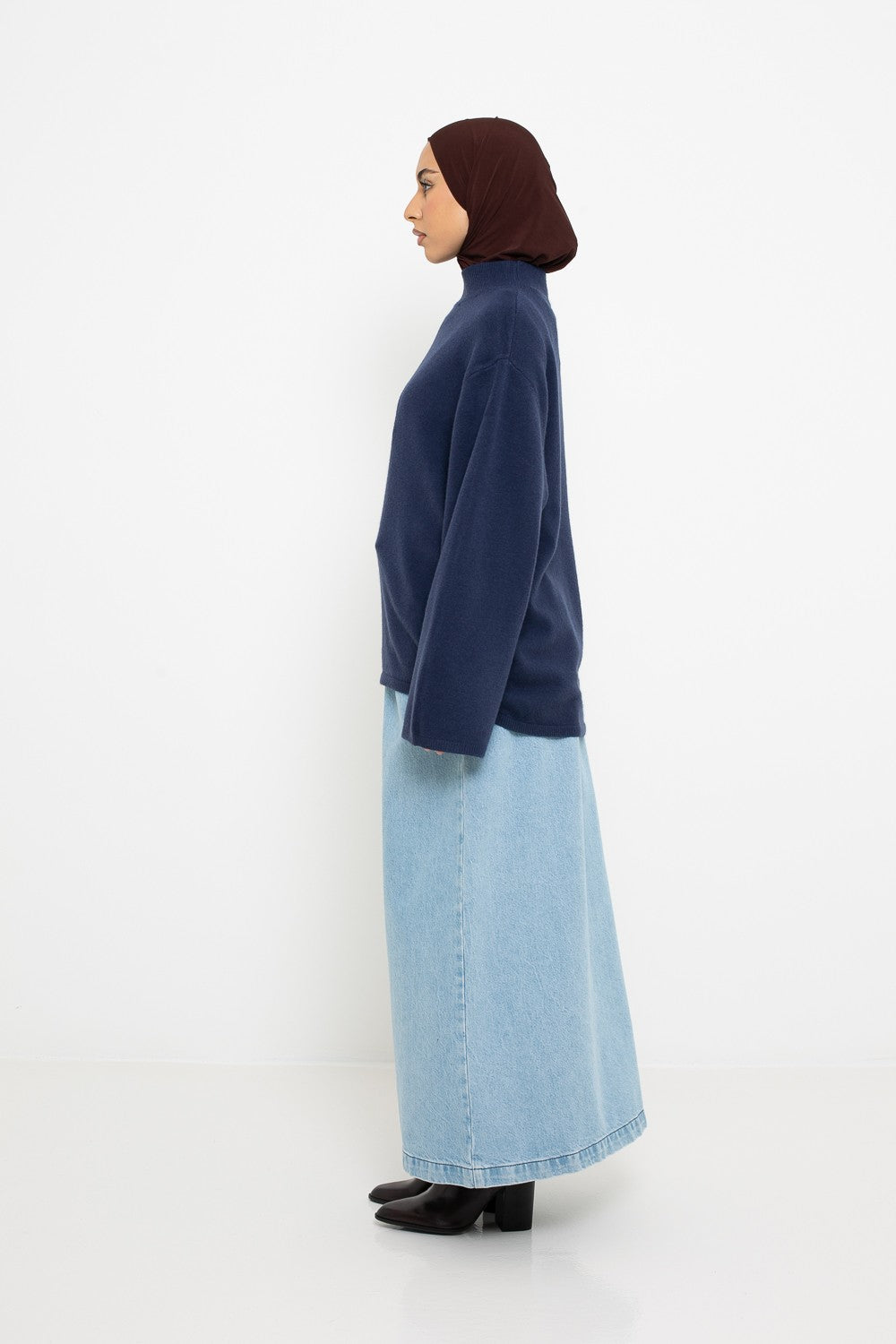 Pull maille fine bleu porté avec une jupe en jean. Profil gauche.Boutique de prêt à porter pour femme musulmane.
