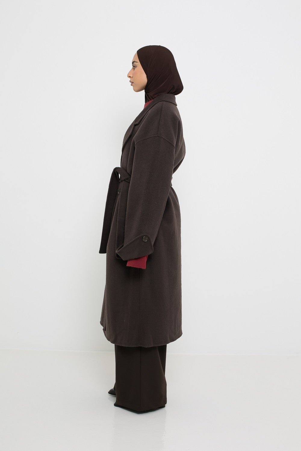 Manteau long en laine marron foncé vue de profil. Pour femme modeste.