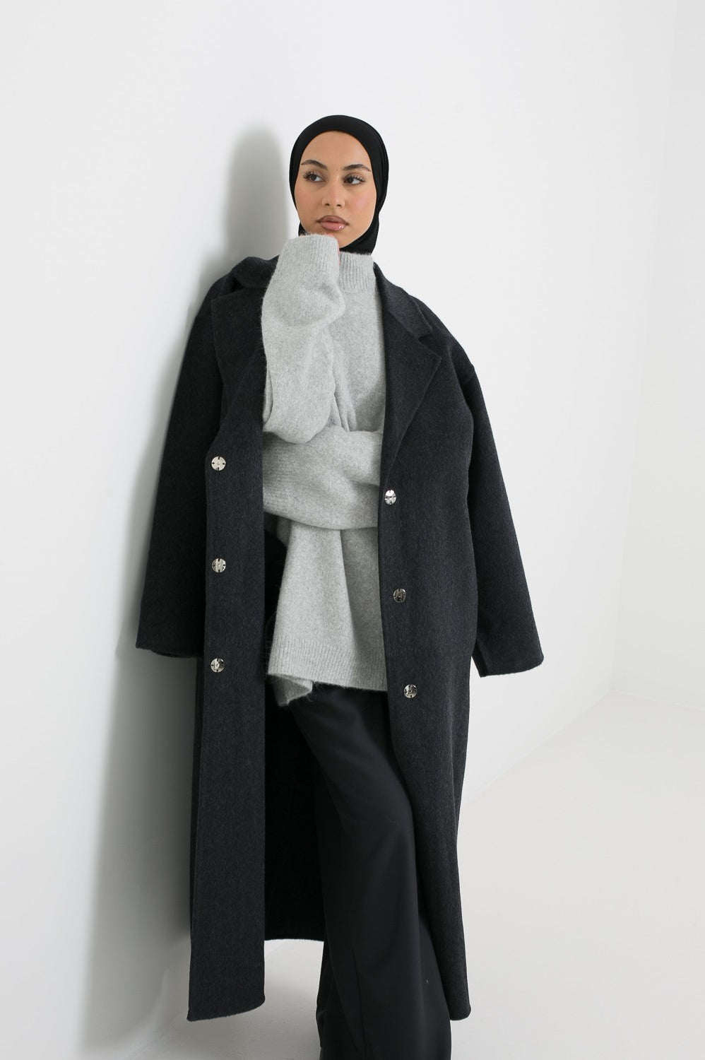 Manteau long en laine gris foncé avec détail bouton à pression. Boutique chic and modesty.