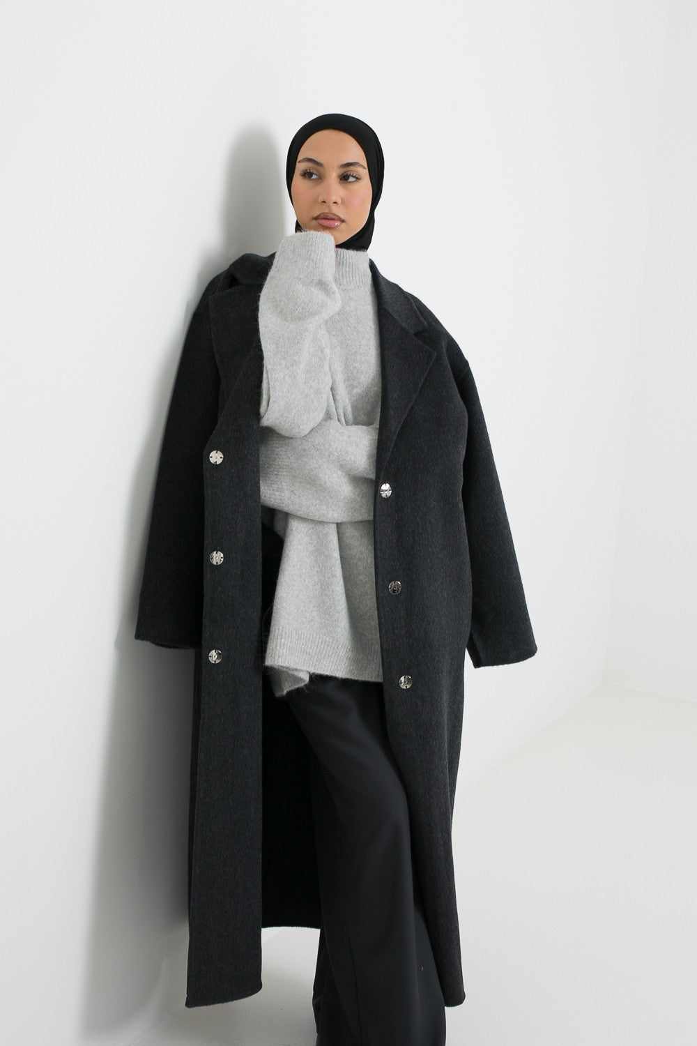 Manteau long en laine gris foncé avec détail bouton à pression. Boutique chic and modesty.