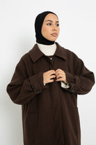 Détail col et bouton du manteau long marron foncé.