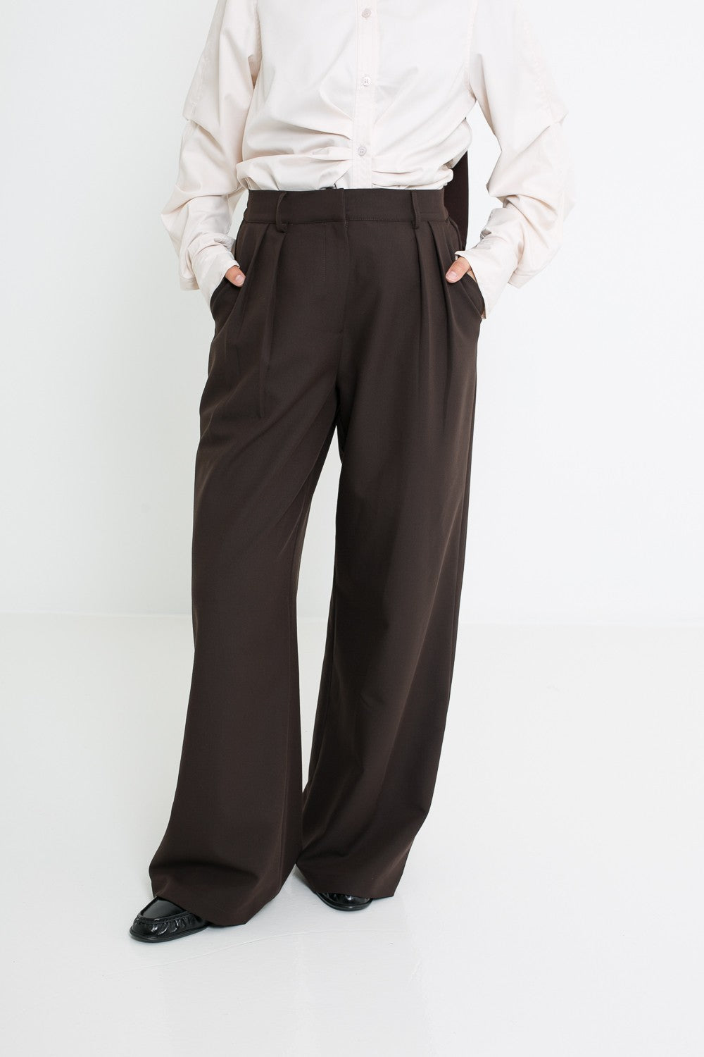Pantalon à pinces marron fonce détails plis, poches et ceinture.