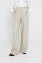 Pantalon ample tailleur pour femme. Détail plis ceinture et poche.