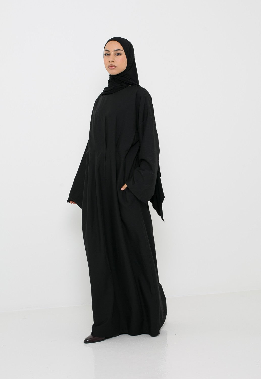 Robe longue classe noire avec plis et coupe structurée, coupe et manche ample pour femme musulmane.